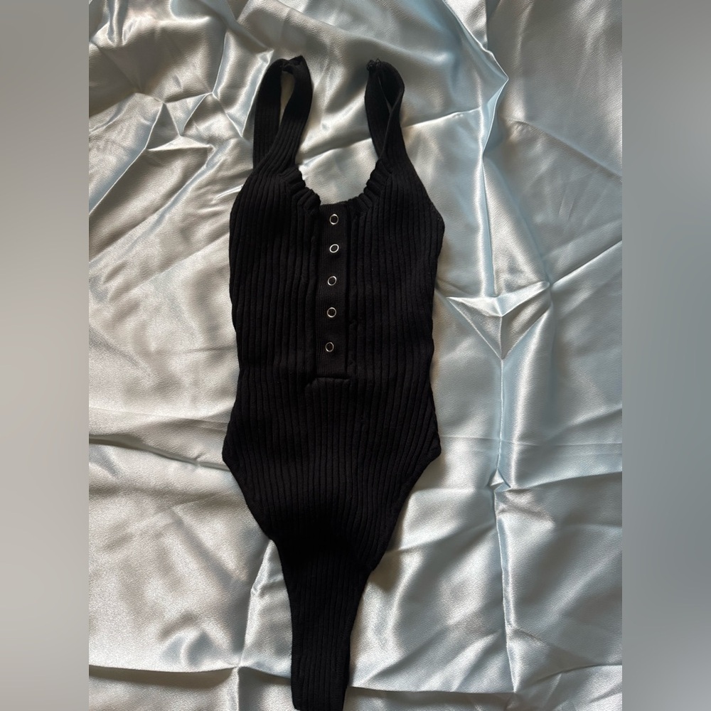 Top Bodysuit in black ribbed material. With bitten detail real buttons on top.